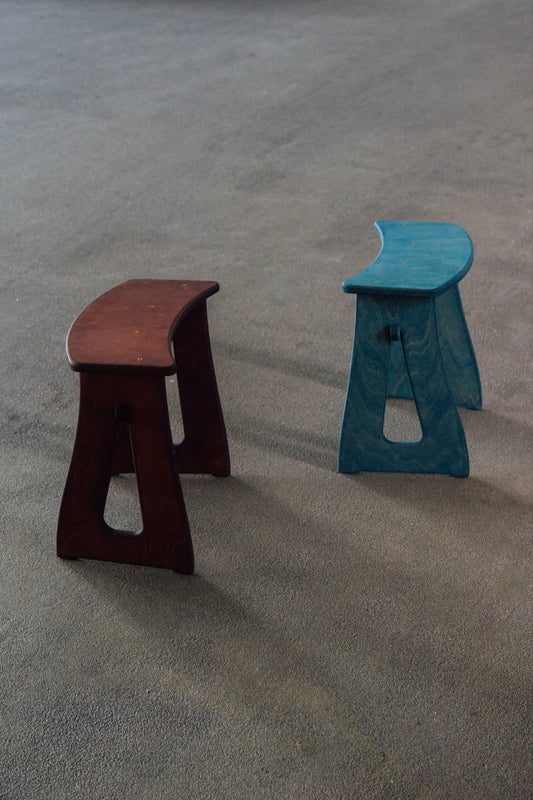 Two stools, one brown and one blue, on a textured gray surface.
